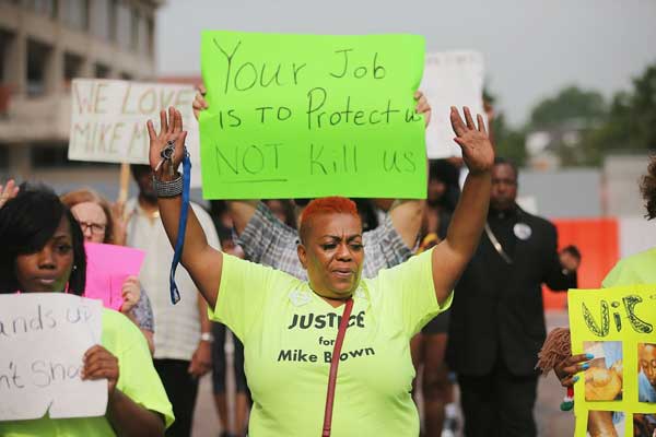Demonstrators protest outside of the Buzz Westfall Justice Center where a grand jury will begin looking at the circumstances surrounding the fatal police shooting of an unarmed teenager Michael Brown on August 19, 2014 in Clayton, Missouri. Brown was shot and killed by a Ferguson, Missouri police officer on August 9. PHOTO | AFP