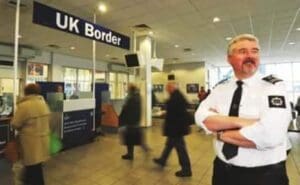 Illegal Kenyans in UK-Passengers going through immigration at a UK airport while an officer keeps an eye