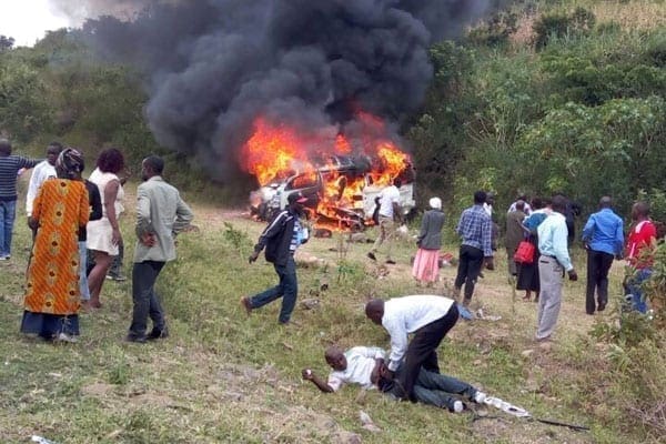 This photo shows the matatu in which mourners were travelling in burning in the background after it rolled several times when its driver veered off the road to avoid hitting an oncoming vehicle on August 26, 2016. PHOTO | COURTESY