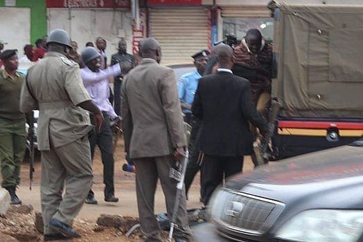 Police try to bundle Eldore-based journalist Duncan Wanga into a police van. PHOTO | COURTESY