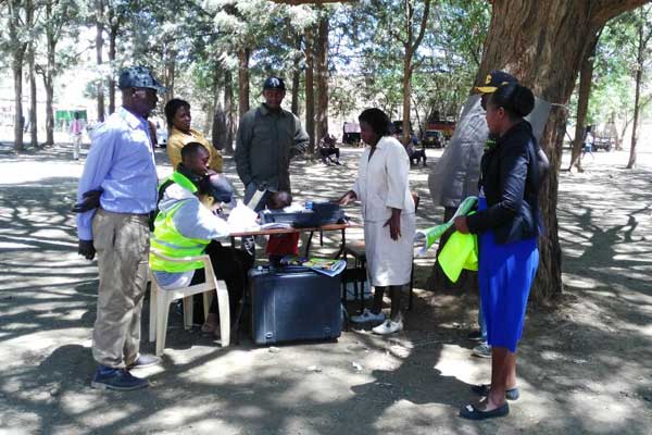Residents register as voters under a tree at