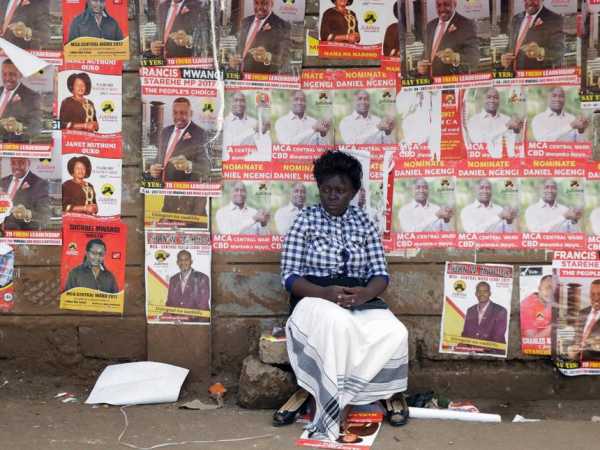 A woman sits in front of campaign posters as she waits to cast her ballot, during the Jubilee Party primary elections, at a polling centre in Nairobi, Kenya April 26, 2017. REUTERS/Thomas Mukoya