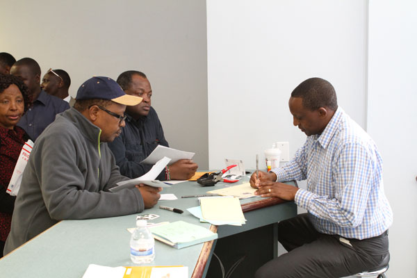 An official from the Kenyan Embassy in Washington (right) registers Kenyans living in Lowell Massachusetts who applied for second generation ID cards on April 20, 2014.  A similar event slated for Georgia this weekend has been called off. PHOTO | SAM MWAURA | Courtesy