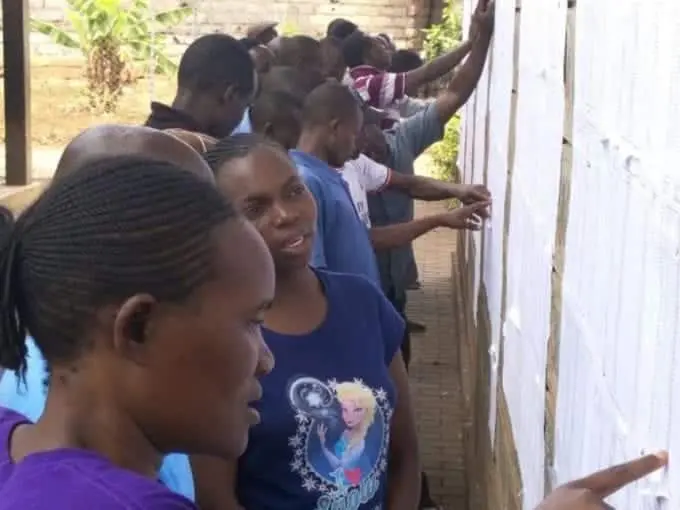Some of dwellers in Mathare confirm whether their names are on IEBC's list of voters. photo/SAMUEL KISIKA