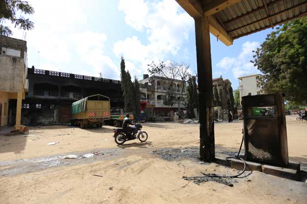 A man rides a motorcycle past a burnt petrol station and a charred building in Mpeketoni, Lamu County, on June 20, 2014. More than 60 people were killed over two days. PHOTO / JOAN PERERUAN