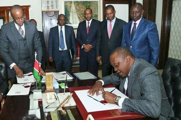 President Uhuru signs Appropriations Act 2016 and Political Parties (Amendment) Act into law at State House, Nairobi, on June 30, 2016. Looking on from right are Deputy President William Ruto, National Assembly Speaker Justus Muturi, Majority Leader Aden Duale, Treasury Cabinet Secretary Henry Rotich and Solicitor General Njee Muturi. PHOTO | PSCU