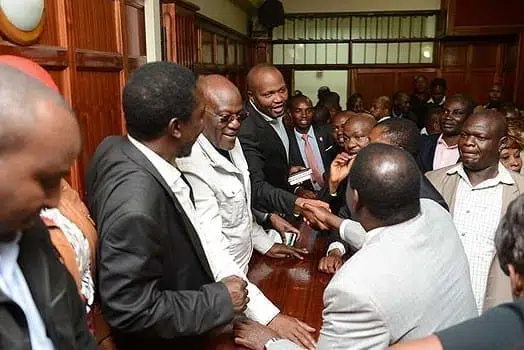 Gatundu South MP Moses Kuria shakes the hand of Cord leader Raila Odinga in court on June 17, 2016.