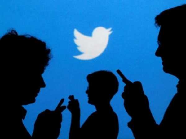 People holding mobile phones are silhouetted against a backdrop projected with the Twitter logo in this illustration picture taken in Warsaw September 27, 2013. REUTERS