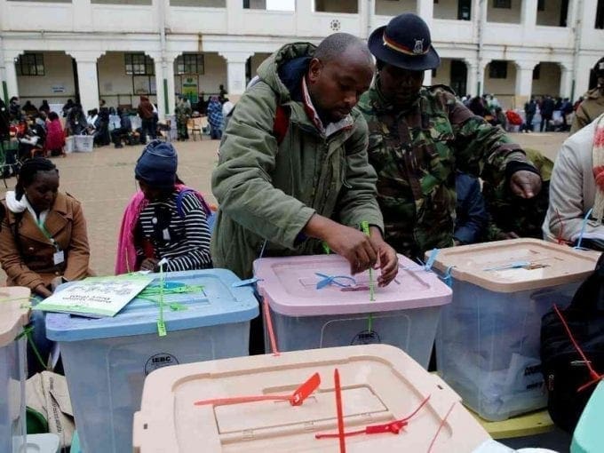 A security policeman and an IEBC election official work on ballot boxes inside the Jamuhuri High School tallying center in Nairobi, August 9, 2017. /REUTERS